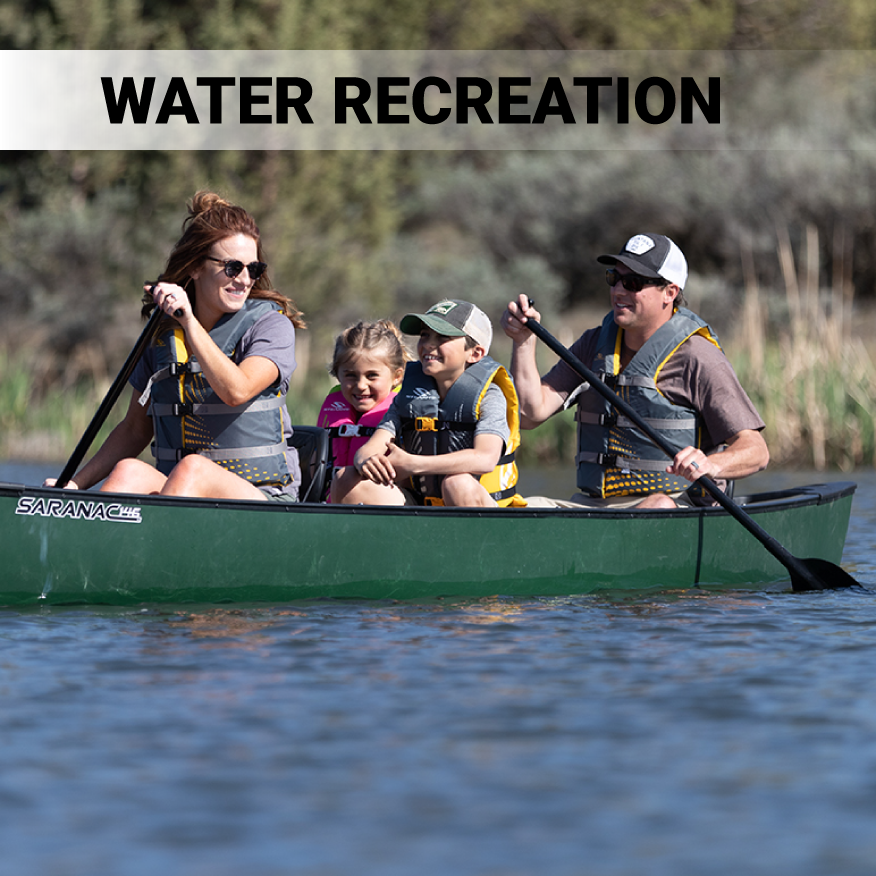 Woman, girl, boy and male family litting in green canoe with Stearns Classic Life Jackets on water.